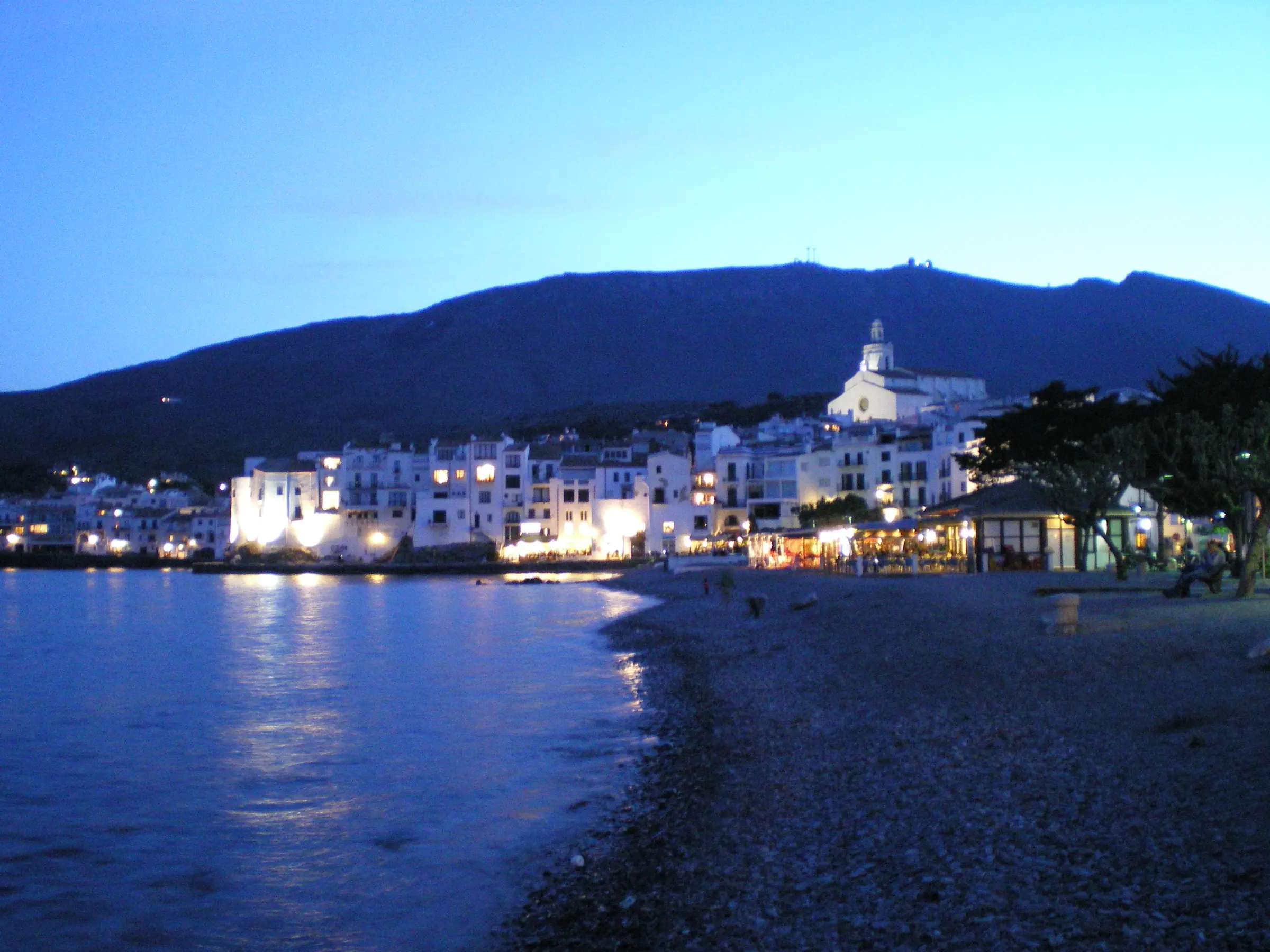 Cadaqués al anochecer con las casas iluminadas junto a la bahía