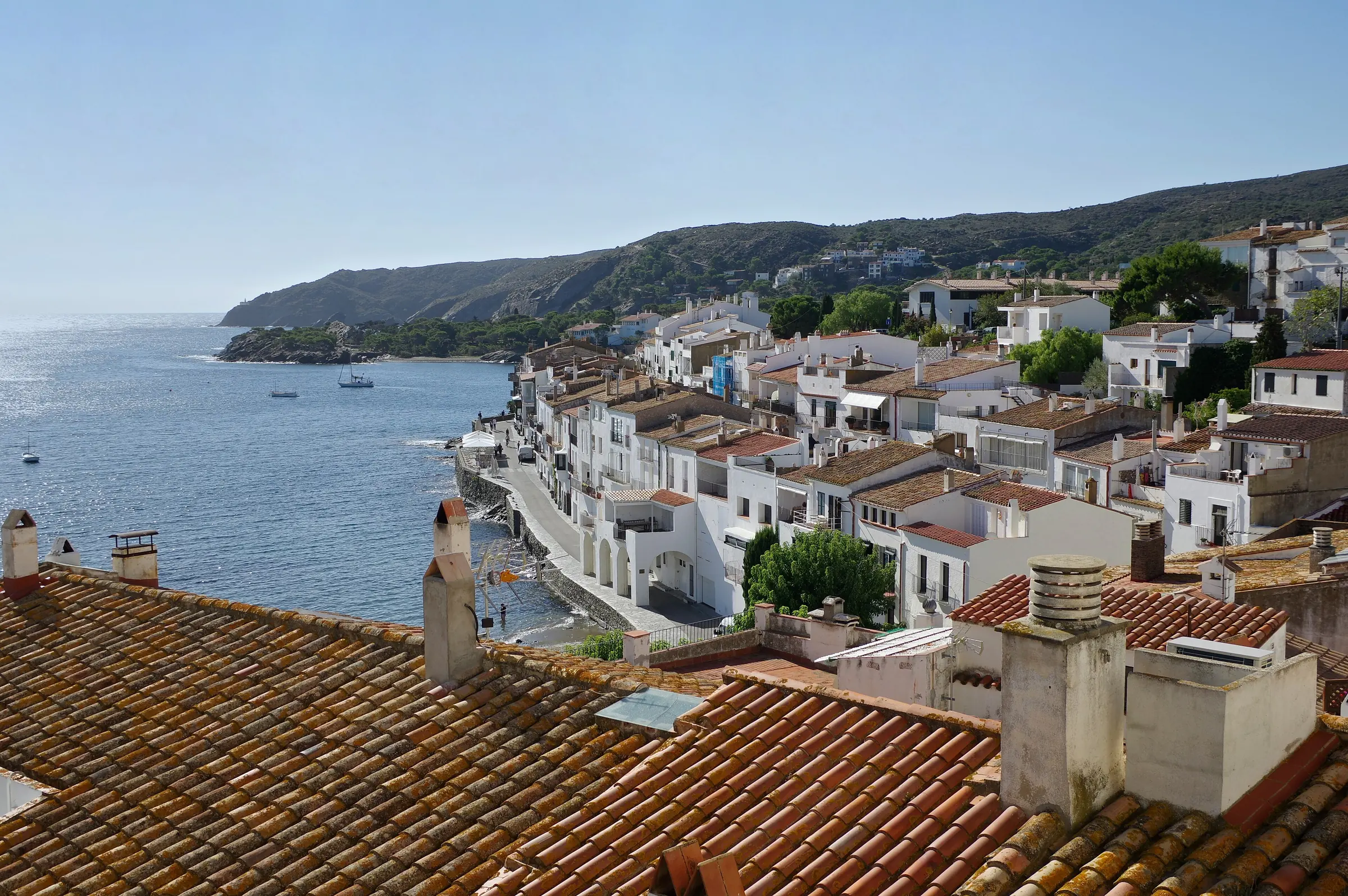 Tejados de teja y casas blancas de Cadaqués descendiendo hasta el mar